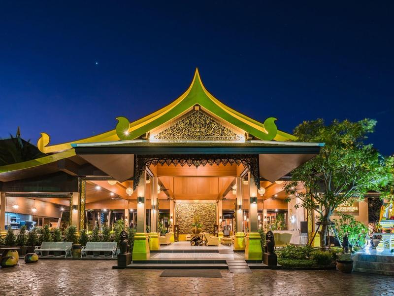 Beleuchtetes Hotel mit traditioneller Architektur bei Nacht und klar blauem Himmel.