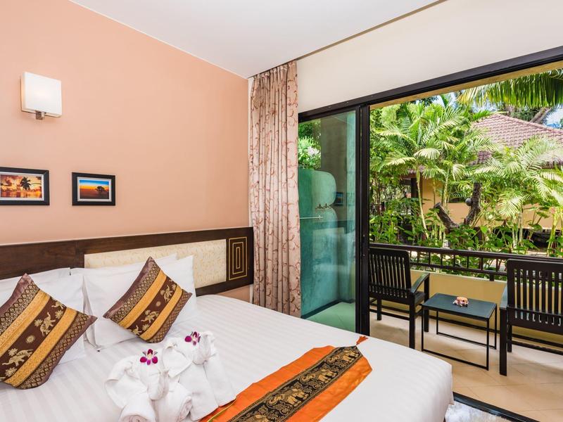 Helles Hotelzimmer mit Doppelbett und Terrasse mit Blick auf tropischen Garten