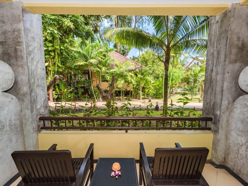 Zwei Stühle mit Tisch auf Balkon mit Blick auf tropischen Garten und Palmen.