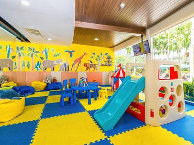 Kolorowy plac zabaw dla dzieci z zjeżdżalnią, pufami i dekoracjami ściennymi z zwierzętami.