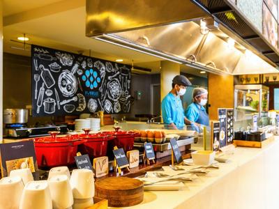 Strefa bufetu z różnymi miskami i dwoma pracownikami w niebieskich mundurach w restauracji.