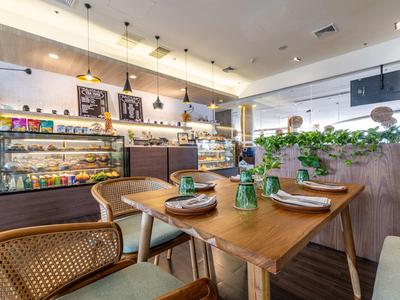 Caffetteria elegante con tavoli in legno, sedie e piante come decorazione in un ambiente moderno.