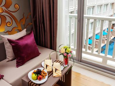 Przytulny kącik z poduszkami, talerzem owoców i widokiem na basen hotelowy.