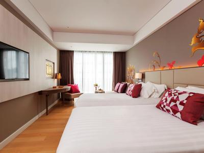 Nowoczesny pokój hotelowy z dwoma łóżkami, dużym telewizorem i biurkiem przy oknie.