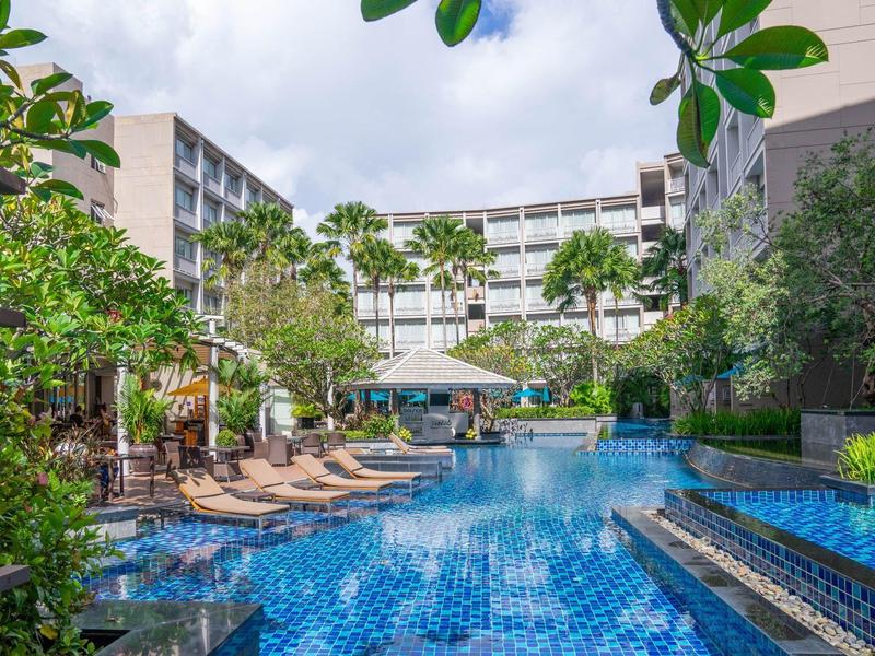 Nowoczesny basen hotelowy z leżakami i palmami w tropikalnym otoczeniu