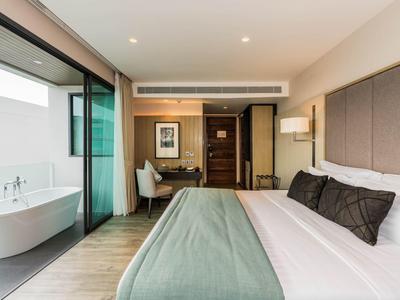 Modern hotelkamer met groot bed, bureau en vrijstaande badkuip op het balkon.