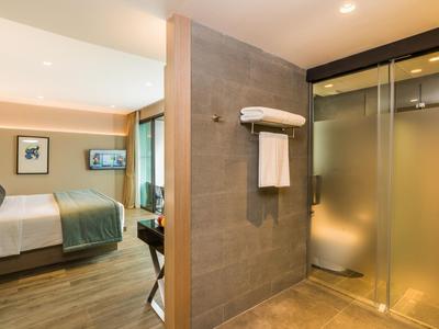 Modern ingerichte hotelkamer met bed en glazen douchewand.