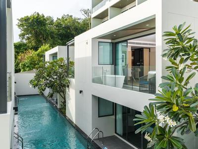 Moderne hotelruimte met zwembad tussen witte gebouwen en weelderig groen.