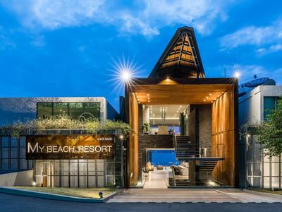 Moderne, verlichte hotelentree bij zonsondergang met heldere lucht.