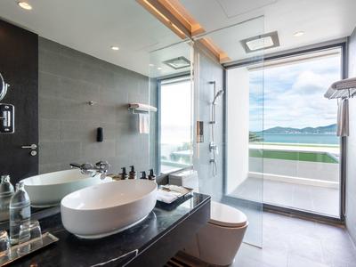 Moderne badkamer met glazen douche en uitzicht op zee.