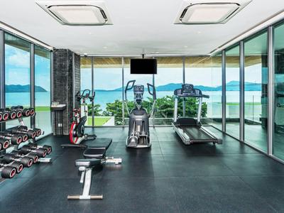Modernes Fitnessstudio mit großer Fensterfront und Blick auf das Meer und Inseln.
