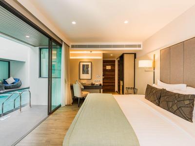 Modern hotelkamer met groot bed en toegang tot het zwembad.