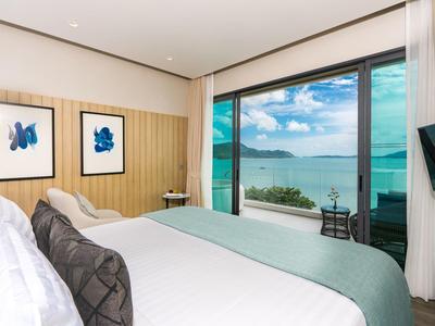 Modern hotelkamer met zeezicht en grote glazen gevel.