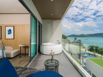 Hotelkamer met balkon, jacuzzi en zeezicht onder een heldere hemel.