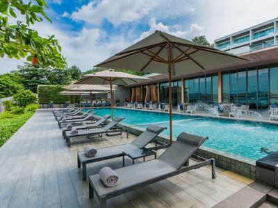 Moderne hotelzwembadomgeving met ligstoelen en parasols onder een blauwe lucht.