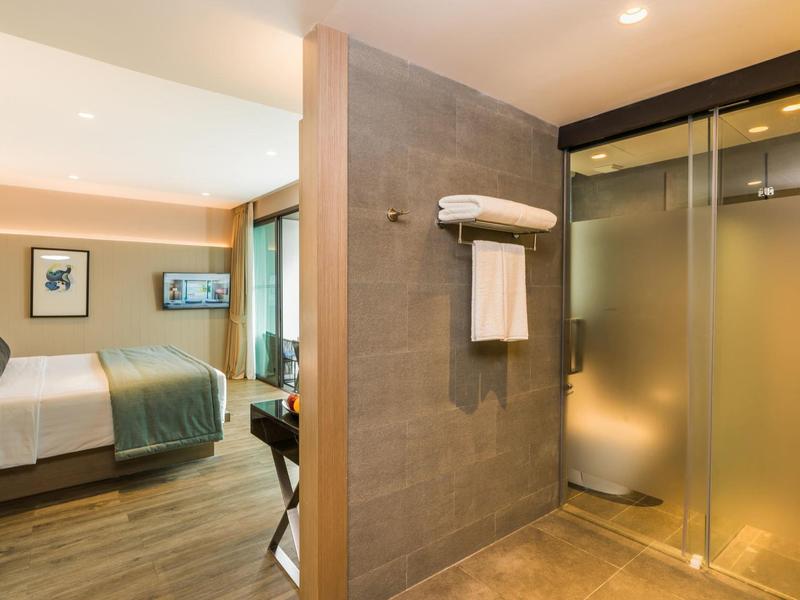 Modern ingerichte hotelkamer met bed en glazen douchewand.