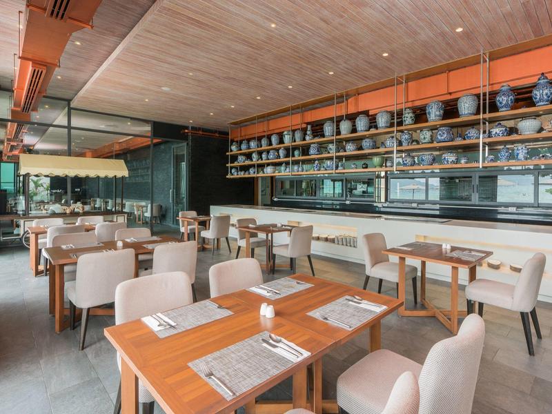 Moderne hotelbar met houten tafels, comfortabele stoelen en planken met servies.