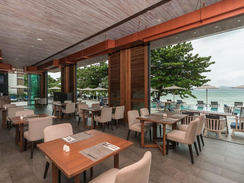 Modern restaurant met uitzicht op zee en grote ramen die daglicht binnenlaten.