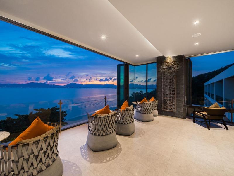 Modern balkon met zitplaatsen en uitzicht op zee en zonsondergang.