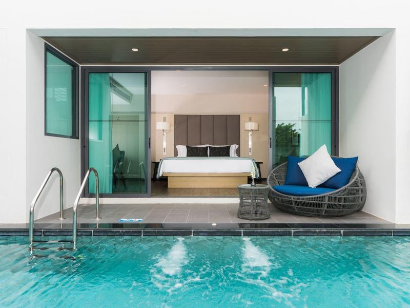 Moderne hotelsuite met open uitzicht op privézwembad en gezellige rotan stoel.