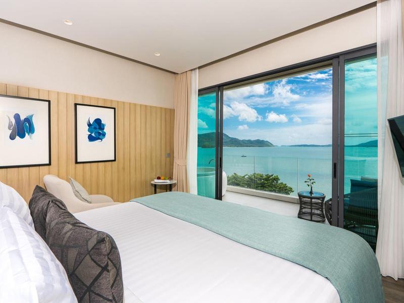 Modern hotelkamer met zeezicht en grote glazen gevel.