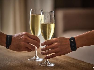 Due mani che brindano con calici di champagne a un tavolo di legno in una stanza accogliente.