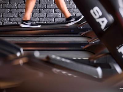 Persona che corre su un tapis roulant in una palestra con parete in mattoni scuri