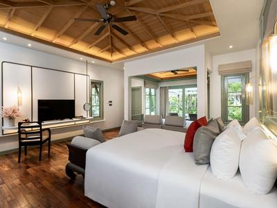 Helle Hotelzimmer mit großem Bett, Holzfußboden und Sitzbereich mit Fernseher.