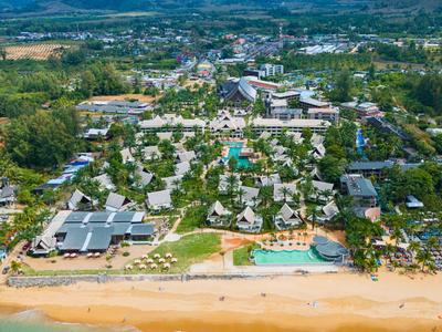 Aerial view of a resort with a beach, pool, and mountains in the background.