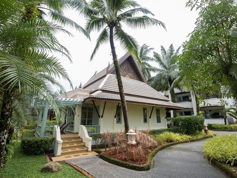 Ein tropisches Resort mit einem weißen Haus, umgeben von Palmen und üppigem Grün.