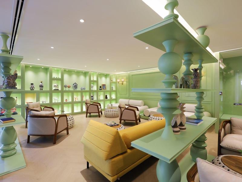 Modern eingerichteter Aufenthaltsraum mit hellgrünen Wänden und bequemen Sitzmöbeln.