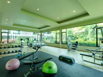 Palestra luminosa con grandi finestre, attrezzature per allenamento e palle fitness colorate.