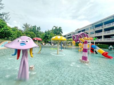 Parco acquatico per bambini con fontane d'acqua a forma di fungo colorato e scivoli davanti a edifici dell'hotel