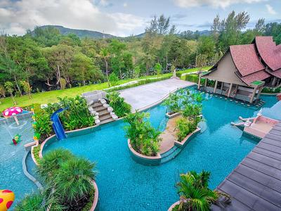 Area piscina di lusso con vegetazione tropicale e edificio tradizionale nel resort.