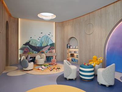 Nowoczesny pokój hotelowy z zabawnym kącikiem dla dzieci, okrągłymi meblami i kolorową ścianą.