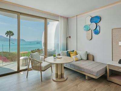 Nowoczesny salon z sofą, krzesłem i stołem, widok na morze przez duże okna.