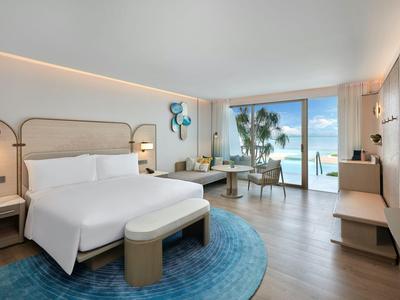 Camera d'hotel moderna con letto grande, tappeto blu e balcone con vista sul mare.