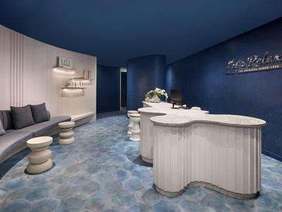 Nowoczesna lobby hotelowa z zakrzywioną recepcją i niebieskimi ścianami.