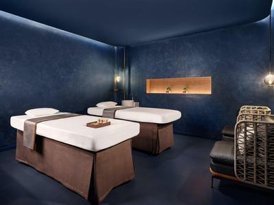 Luksusowy pokój spa z dwoma stołami do masażu i przyciemnionym oświetleniem.