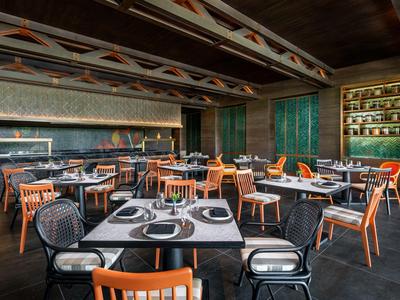 Restaurant d'hôtel moderne avec tables en bois élégantes, chaises et éclairage tamisé.