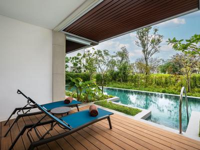 Terrasse en bois avec deux chaises longues et piscine entourée de verdure.