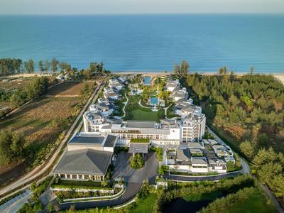 Complexe de luxe avec piscine et jardin au bord de la mer, entouré de forêt et de champs ouverts.