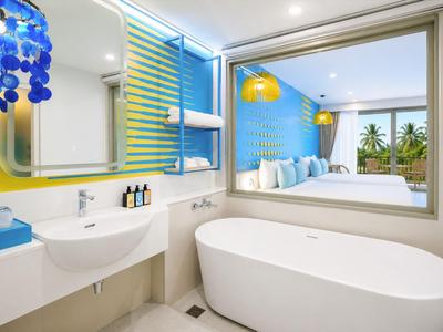 Bagno moderno in hotel con vasca autonoma, grande specchio e accenti blu.
