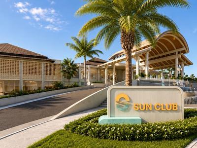 Ingresso di un resort soleggiato con palme e cielo azzurro limpido.