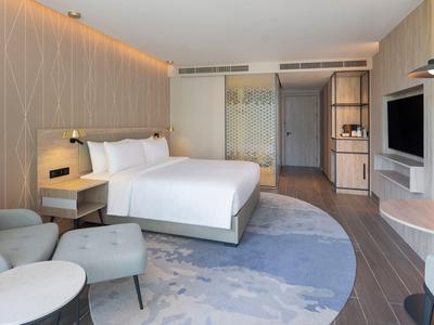 Camera d'hotel moderna con letto matrimoniale, angolo salotto e TV a schermo piatto.