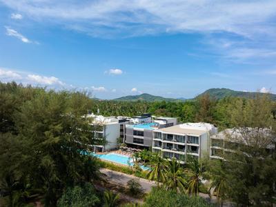Edificio dell'hotel con piscina circondato da paesaggio verde e colline sotto un cielo blu.