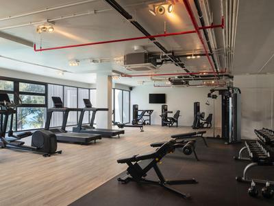 Una palestra moderna con tapis roulant, macchine per allenamento e manubri in una stanza luminosa.
