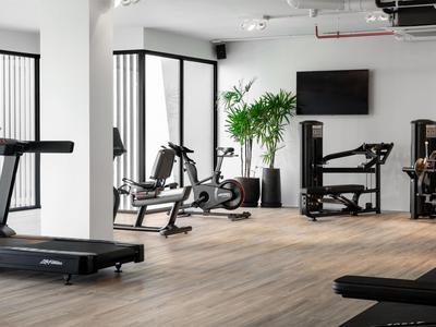 Palestra moderna con tapis roulant, cyclette e pesi in una luminosa area dell’hotel.