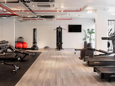 Palestra moderna con tapis roulant, manubri e attrezzi per allenamento forza in hotel.