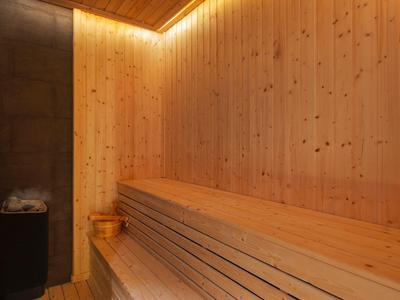 Sauna in legno con panche a più livelli e luce soffusa in un hotel.